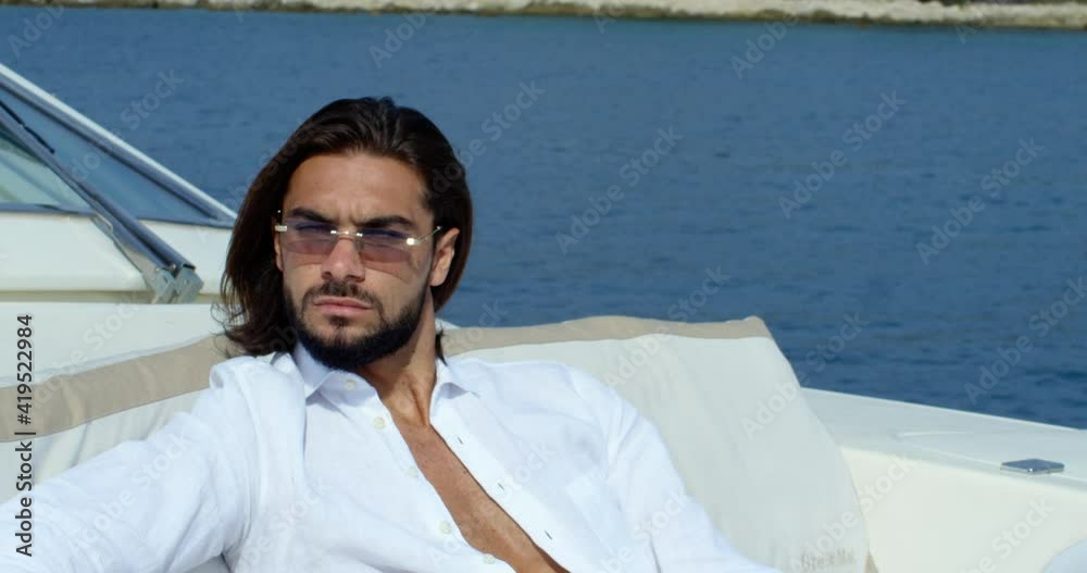 Close view of a man with long brown hair lies on a sofa in a boat under the blue sky - Cinematic scene with RED Camera 4K Close view of a man with long brown hair lies on a sofa in a boat under the blue sky - Cinematic scene with RED Camera 4K