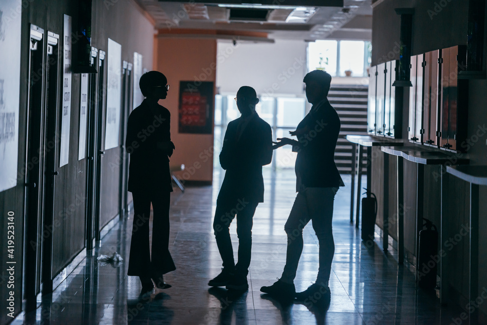 Silhouettes of business people standing in a corporate building.