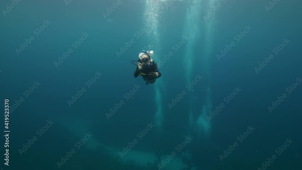 Slow Motion: Man With Camera Gesturing While Scuba Diving In Sea Slow Motion: Man With Camera Gesturing While Scuba Diving In Sea