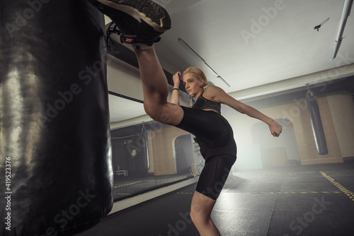 Young adult sexy woman doing back leg high kick during kickboxing.