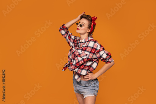 Studio shot of beautiful young woman with blond hair in pinup style clothes posing