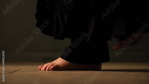closeup of barefoot feets with black trousers moving, turn, jump and dance on a brown floor photo