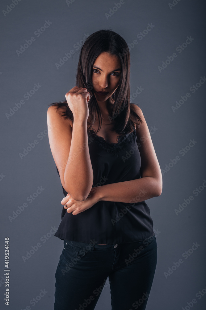 Sensual studio portrait of a sexy woman standing with one arm crossed on a gray background Sensual studio portrait of a sexy woman standing with one arm crossed on a gray background