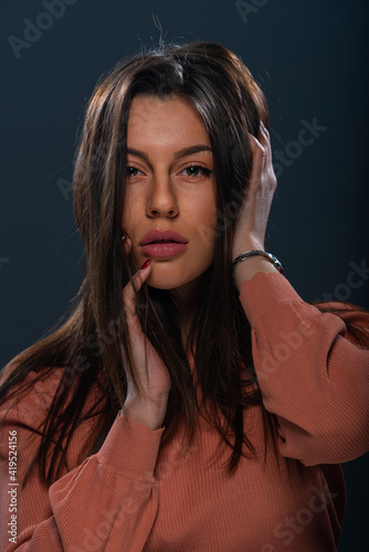 Close up portrait of beautiful young female model with orange blouse on black background