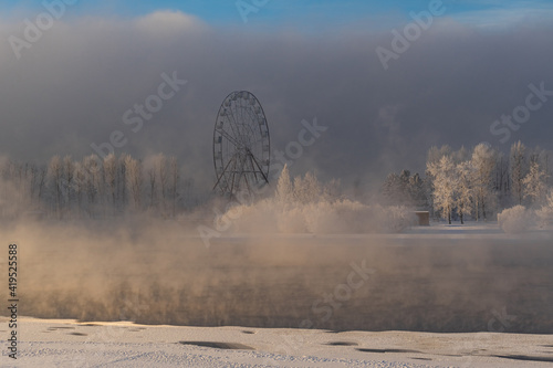 Ferris wheel on the bank of the Angara in the morning fog photo