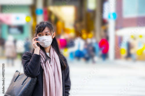 A young Asian woman talking on mobile phone in the city street