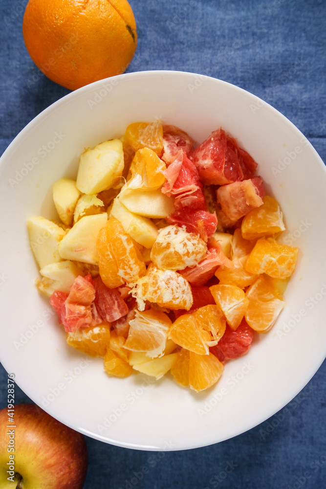 TOp view of various fruit in the white bowl on the table at home - fruit salad healthy eating concept vegan or vegetarian food ready to eat TOp view of various fruit in the white bowl on the table at home - fruit salad healthy eating concept vegan or vegetarian food ready to eat