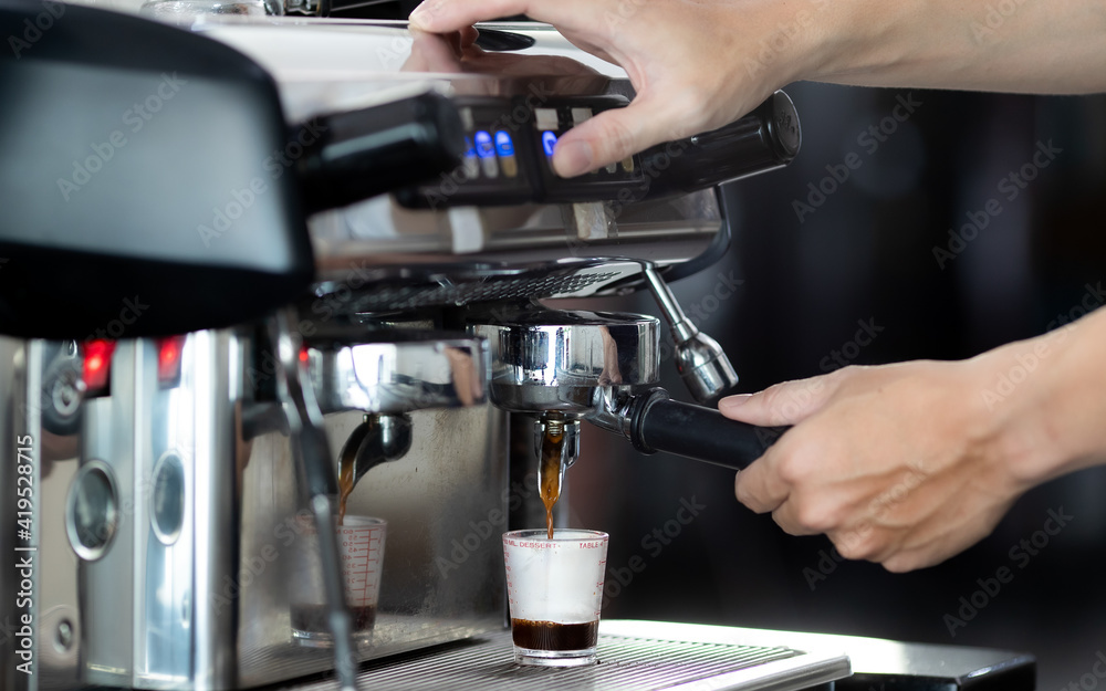 Close up hand holding of making coffee with machine in cafe. Professional modern espresso coffee machine pours hot drink into the cup. Concept coffee in cafe.
