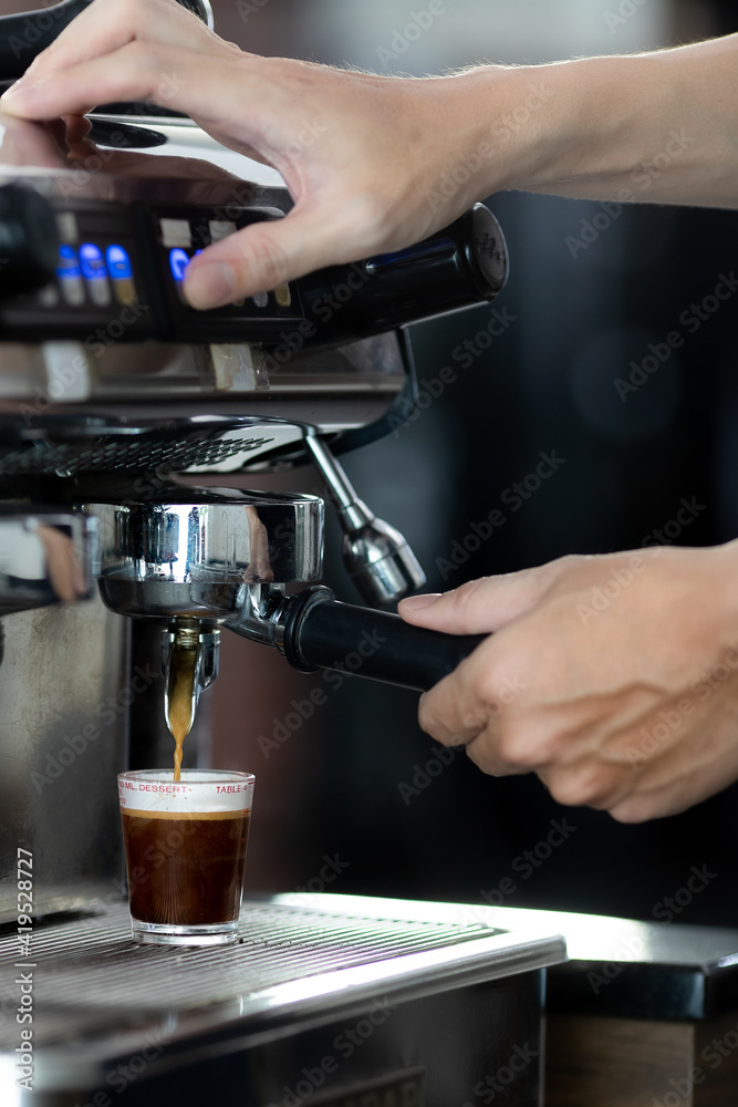 Close up hand holding of making coffee with machine in cafe. Professional modern espresso coffee machine pours hot drink into the cup. Concept coffee in cafe.