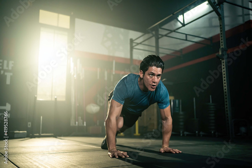 Caucasian young man doing cardio exercise by running plank pose in gym