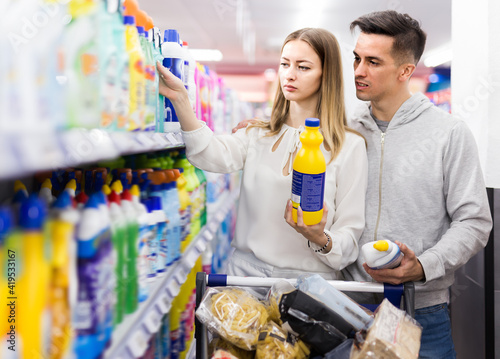 Ordinary couple doing shopping together, choosing household detergents in store