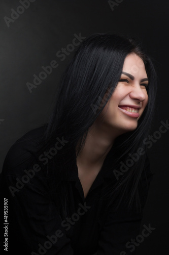 Studio portrait of a brunette in black clothes on a dark background