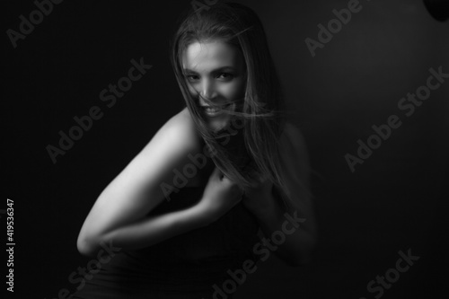 black and white portrait of an adult woman in a studio on black background.