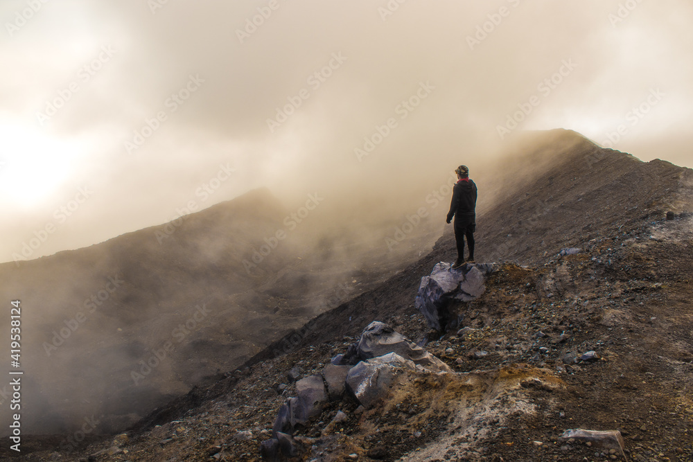 Middle-aged man contemplating alone the arid volcanic landscape in a cloudy early morning