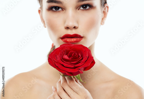 Portrait of romantic people with bare shoulders and a red flower in front of their eyes