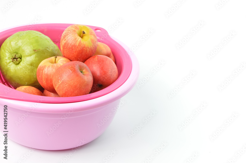 Bunch of apples and guava fruit in a plastic bowl over white background. Bunch of apples and guava fruit in a plastic bowl over white background.