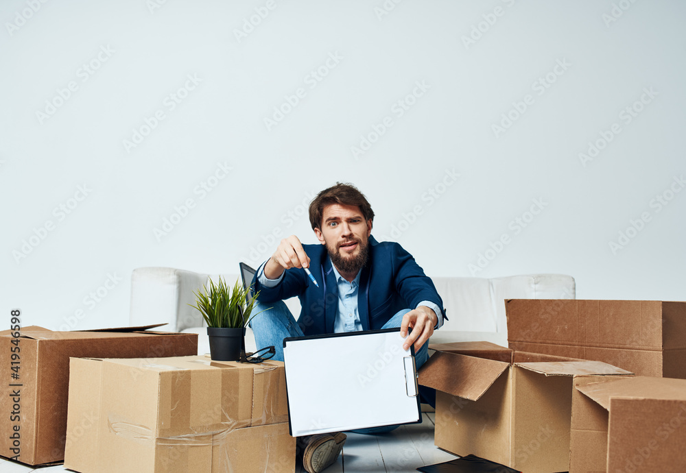 Business man sitting on the floor with boxes unpacking documents to the office manager Business man sitting on the floor with boxes unpacking documents to the office manager