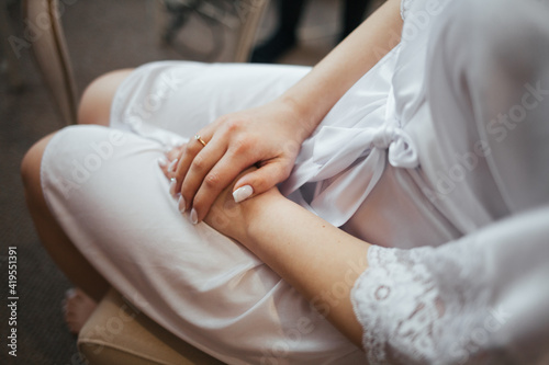 Women's hands with French manicure. The girl put her hands in her lap. A beautiful girl in a dressing gown.