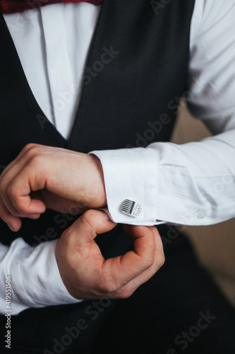 A man in a business suit. The man fastens his cufflinks. A man dresses for a business meeting.