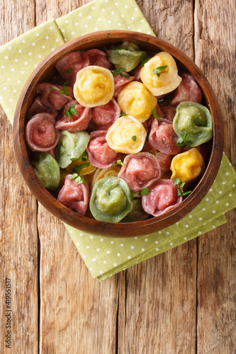 Italian pasta tortellini from colored dough close-up in a bowl on the table. vertical top view from above