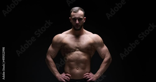 Shirtless muscular man flexing muscles over black background photo