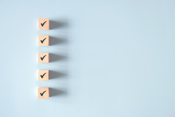 Wood cube with check mark on blue background, Checklist concept, Copy space.