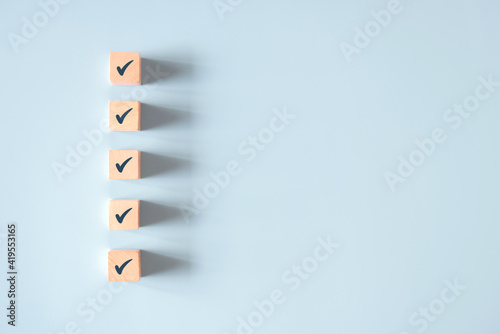 Wood cube with check mark on blue background, Checklist concept, Copy space. photo