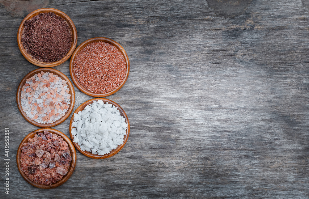 Several types of salt on a wooden background