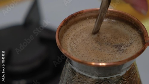 Natural coffee is brewed in a coffee maker. a woman's hand stirs the coffee with a long spoon. foam for coffee.
