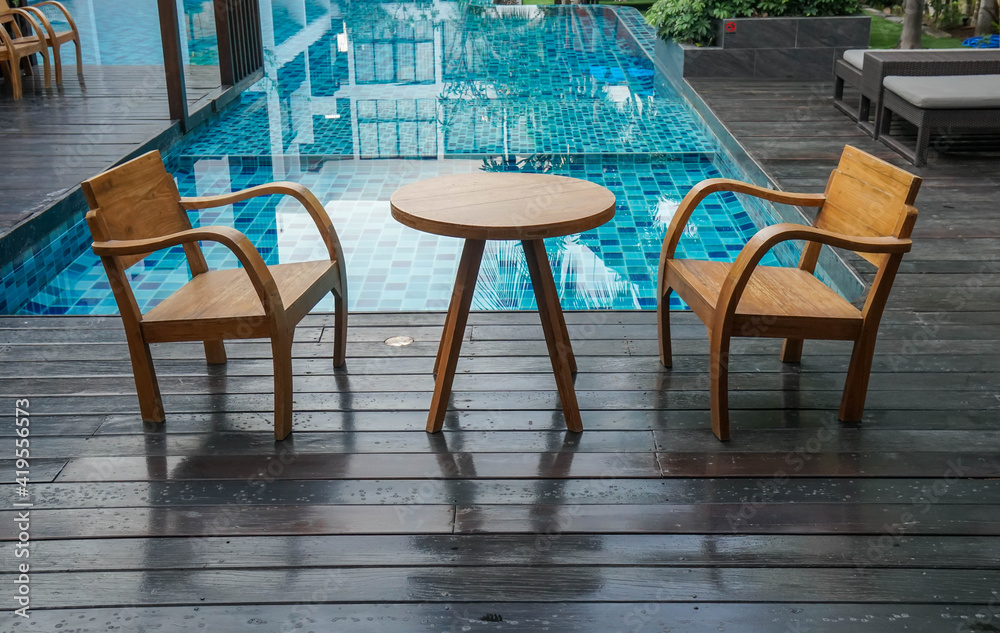 wooden table and chairs at the poolside for breakfast in luxury hotel