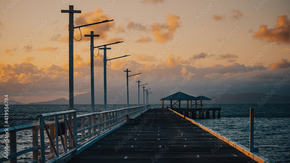A long jetty and wooden dock by the pier out to sea at sunset, Magnetic Island, Queensland, Australia.