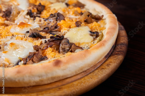 Pizza with cheese and mushrooms on a wooden plate. Close-up, selective focus