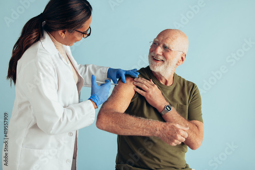 Fotografie Doctor giving vaccination to elderly man