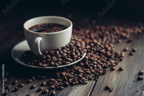 fragrant coffee beans on a wooden table and a cup with a hot drink on a saucer