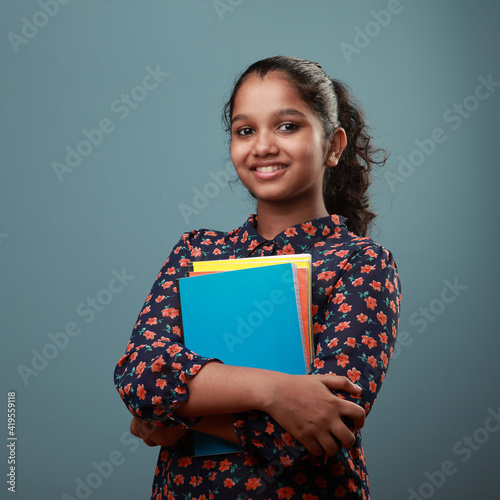 Happy young girl holding note books in her hand photo