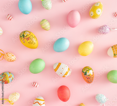 Creative pattern of colorful Easter eggs of different materials, colors and size. Flat lay concept on pastel pink background.