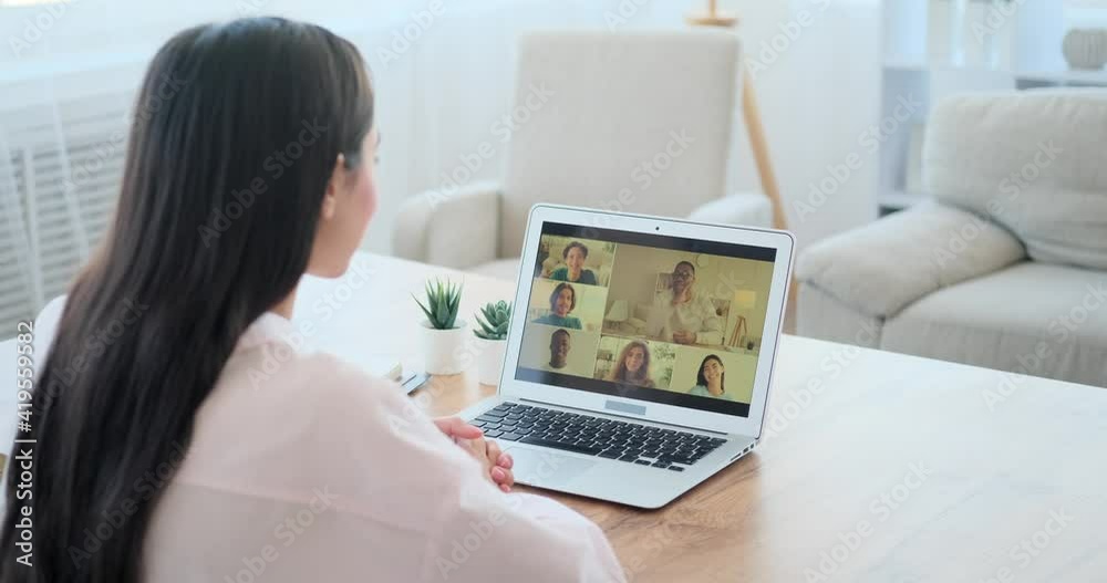 Woman video chatting with colleagues using laptop at office Woman video chatting with colleagues using laptop at office