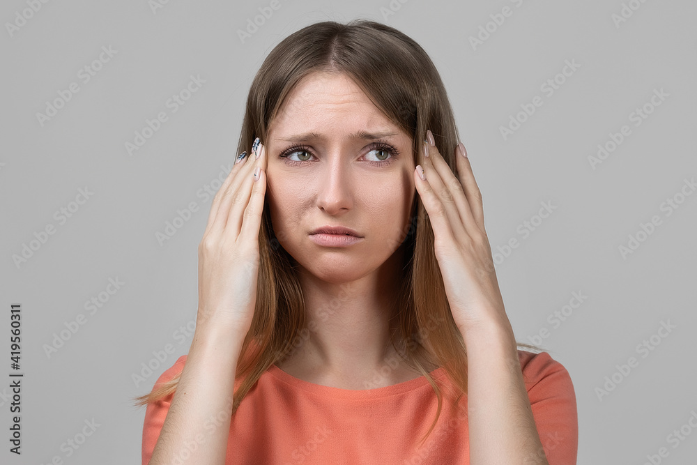 Concerned, frustrated young blond girl feeling fatigue, as suffer pain in head, painful headache or migraine Concerned, frustrated young blond girl feeling fatigue, as suffer pain in head, painful headache or migraine