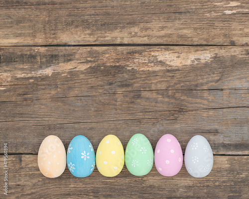 Painted multicolored Easter eggs arranged in a row lying on a wooden background	