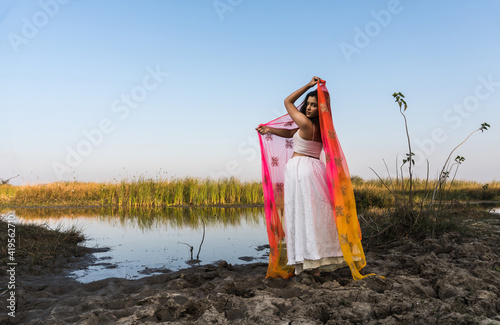 Portrait of beautiful Indian girl wearing Indian traditional dress. Young woman in traditional Indian costume lehenga choli with fashionable hairstyle poses photo