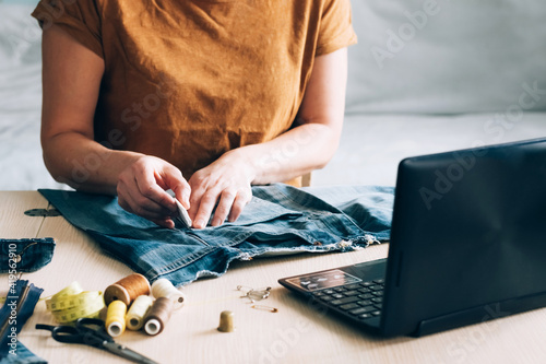 A woman is engaged in online training and looks at sewing lessons on a laptop