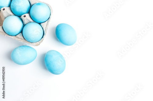 Happy Easter concept. Chicken eggs painted in blue color in the egg compartment. Preparation for holiday. White background copy space