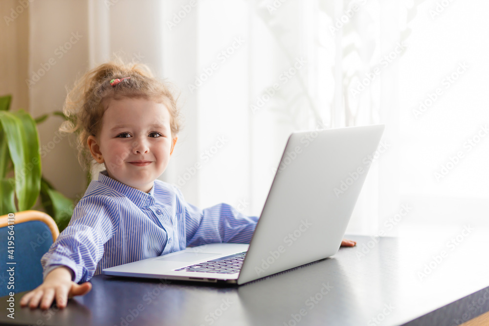 little smiling preschooler girl studying at computer. kid playing online games. remote education of small children. modern development child at laptop. homeschooling, learning distaning concept. little smiling preschooler girl studying at computer. kid playing online games. remote education of small children. modern development child at laptop. homeschooling, learning distaning concept.