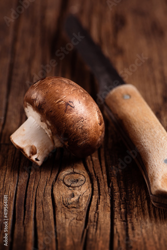 Obraz na płótnie Cremini mushroom and kitchen knife on textured wood background. One baby portobello. Closeup. w salonie