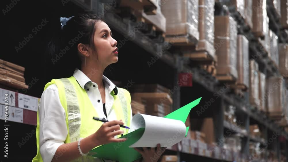Asian Staff woman order details on tablet computer for checking goods and supplies on shelves with goods background in warehouse.logistic and business export. Asian Staff woman order details on tablet computer for checking goods and supplies on shelves with goods background in warehouse.logistic and business export.