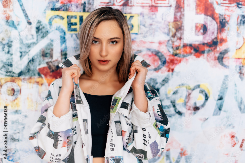 Fototapeta premium fashionable woman with graffitti style background coloured blazer jacket business crazy style blue jeans black top sexy