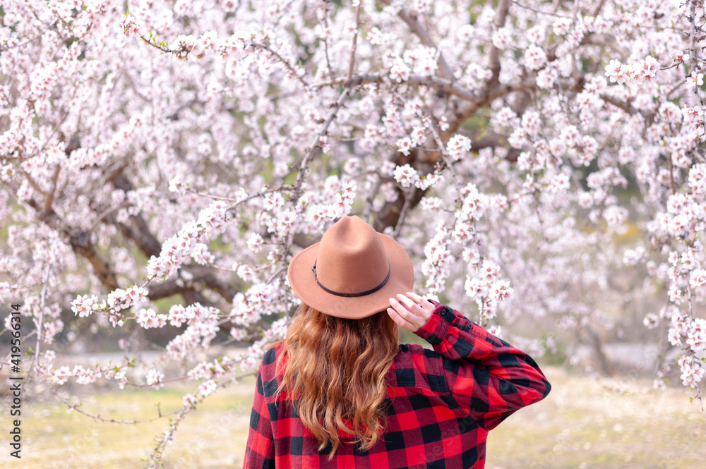 Woman's back in front of a blossom pink almond tree