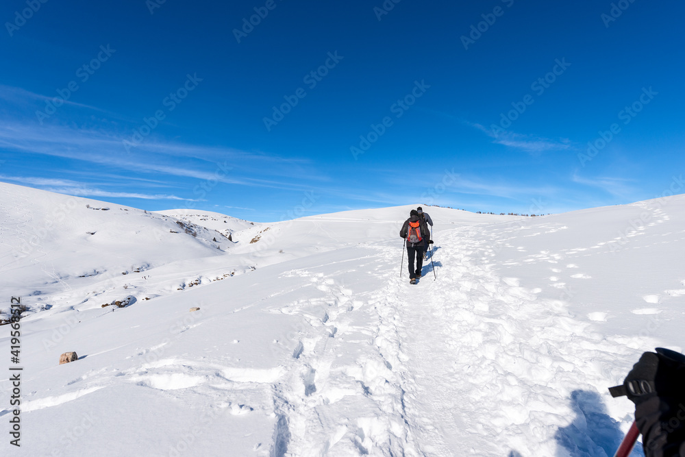 Two Hikers on a snowy footpath in winter landscape on the Lessinia Plateau (Altopiano della Lessinia), Regional Natural Park near Malga San Giorgio ski resort, Verona province, Veneto, Italy, Europe.