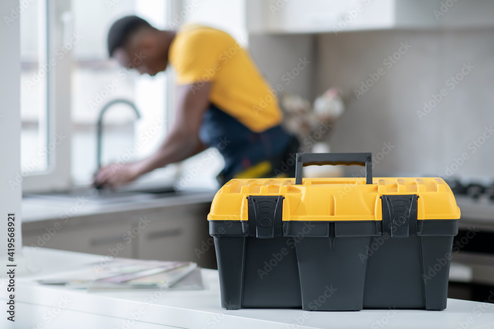 Dark-skinned service man working in the kitchen and looking concentrated on work Dark-skinned service man working in the kitchen and looking concentrated on work