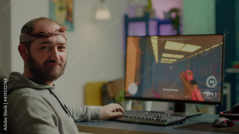Pro cyber man looking at camera before playing space shooter videogames using professional RGB keypad on powerful computer. Professional player performing during online gaming championship late night Pro cyber man looking at camera before playing space shooter videogames using professional RGB keypad on powerful computer. Professional player performing during online gaming championship late night